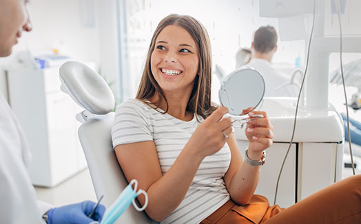 Woman examining smile at dental office